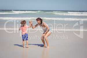 Boy giving high five to mother on shore