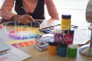 Mid section of businesswoman working on digitizer at office