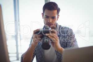 Photo editor holding camera while sitting in office