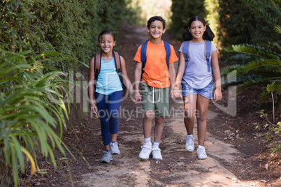 Portrait of smiling friends carrying backpack at natural parkland