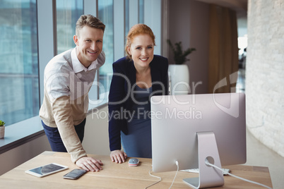 Portrait of smiling executives standing at desk