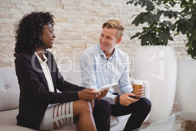 Smiling executives interacting on sofa