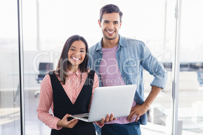 Portrait of smiling colleagues with laptop