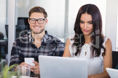 Smiling businessman sitting with female colleague at office