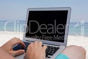 Man using laptop while resting at beach