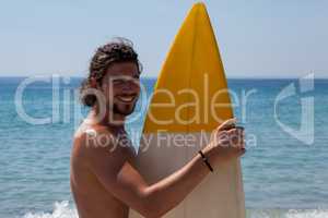 Smiling surfer with surfboard standing at beach coast