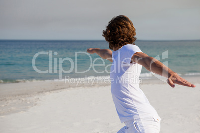 Man performing yoga at beach