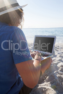 Man using laptop on the beach