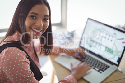 High angle portrait of smiling businesswoman working on laptop at office