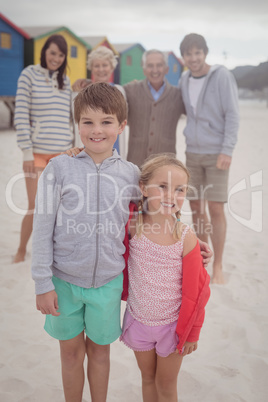 Portrait of happy siblings standing with parents in background