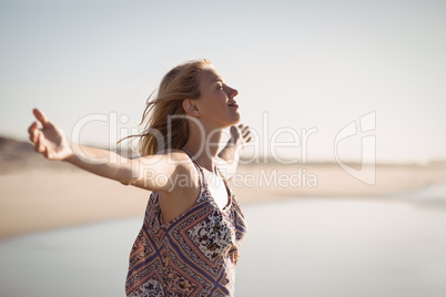 Happy woman with arms outstretched standing at beach