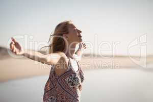 Happy woman with arms outstretched standing at beach