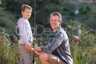 Father and son with fishing rod on field