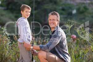 Father and son with fishing rod on field