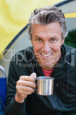Man holding cup by tent at campsite