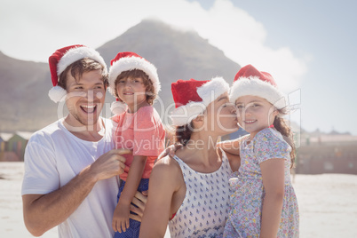 Cheerful family wearing Santa hat at beach