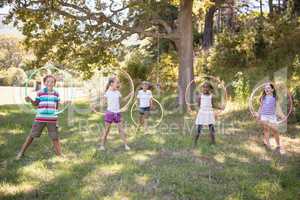 Group of cheerful friends playing with hula hoops at campsite