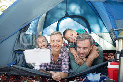 Smiling family taking selfie in the tent