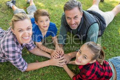 Happy family lying and putting their hands together in park
