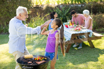 Grandfather and granddaughter giving a high five while preparing barbecue
