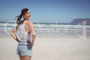Portrait of happy woman with hands on hip standing at beach