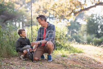 Father and son looking at each other while holding fishing rod