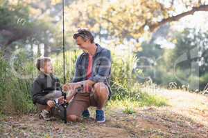 Father and son looking at each other while holding fishing rod