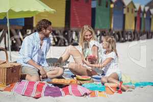 Happy family sitting together on blanket at beach