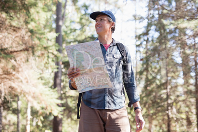 Low angle view of hiker with map standing in forest