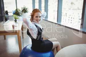 Portrait of smiling executive exercising on fitness ball