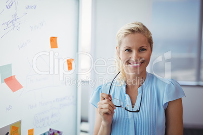 Portrait of smiling executive holding spectacles