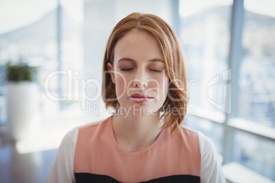 Beautiful executive meditating in office