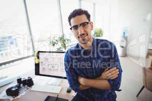 Portrait of graphic designer standing with arms crossed at desk