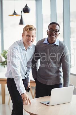 Portrait of smiling executives using laptop