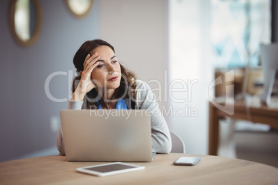 Thoughtful executive sitting with laptop at desk