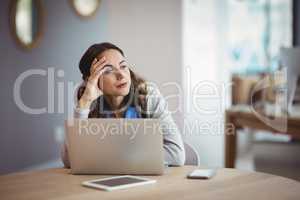 Thoughtful executive sitting with laptop at desk