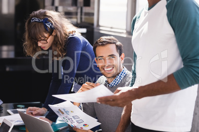 Portrait of businessman sitting by colleagues