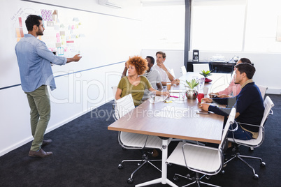 Colleagues looking at businessman explaining in office