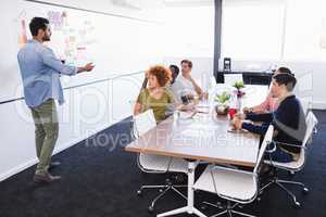 Colleagues looking at businessman explaining in office