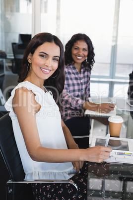 Portrait of businesswoman with female colleague sitting at creative office
