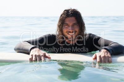 Surfer leaning on surfboard in sea