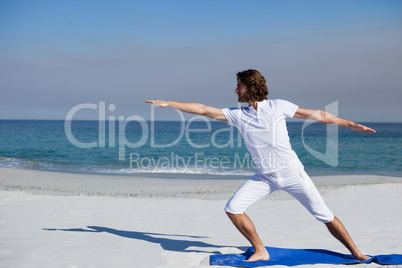 Man performing yoga at beach