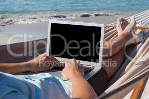 Man using laptop while relaxing on hammock