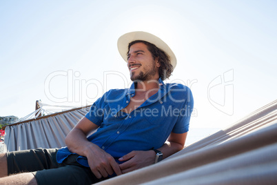 Smiling looking away while relaxing on hammock at beach
