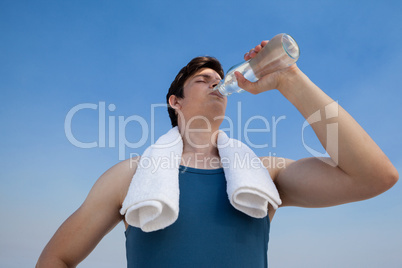 Man drinking water from bottle at beach