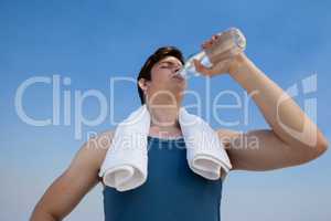 Man drinking water from bottle at beach