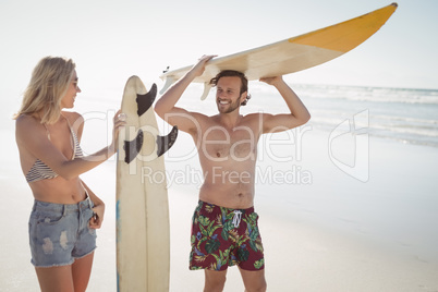 Happy couple holding surfboard at beach