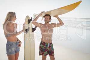 Happy couple holding surfboard at beach