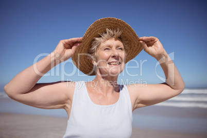 Smiling senior woman wearing sun hat at beach