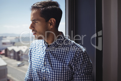 Thoughtful businessman looking through glass window